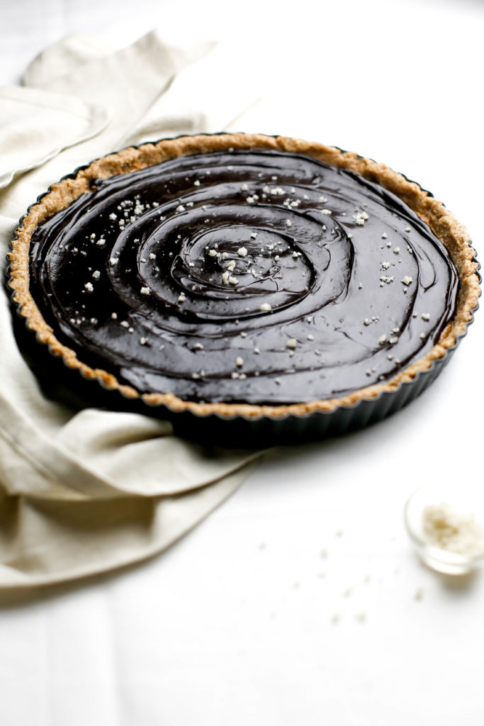 chocolate almond butter tart with a bowl of sea salt and napkin