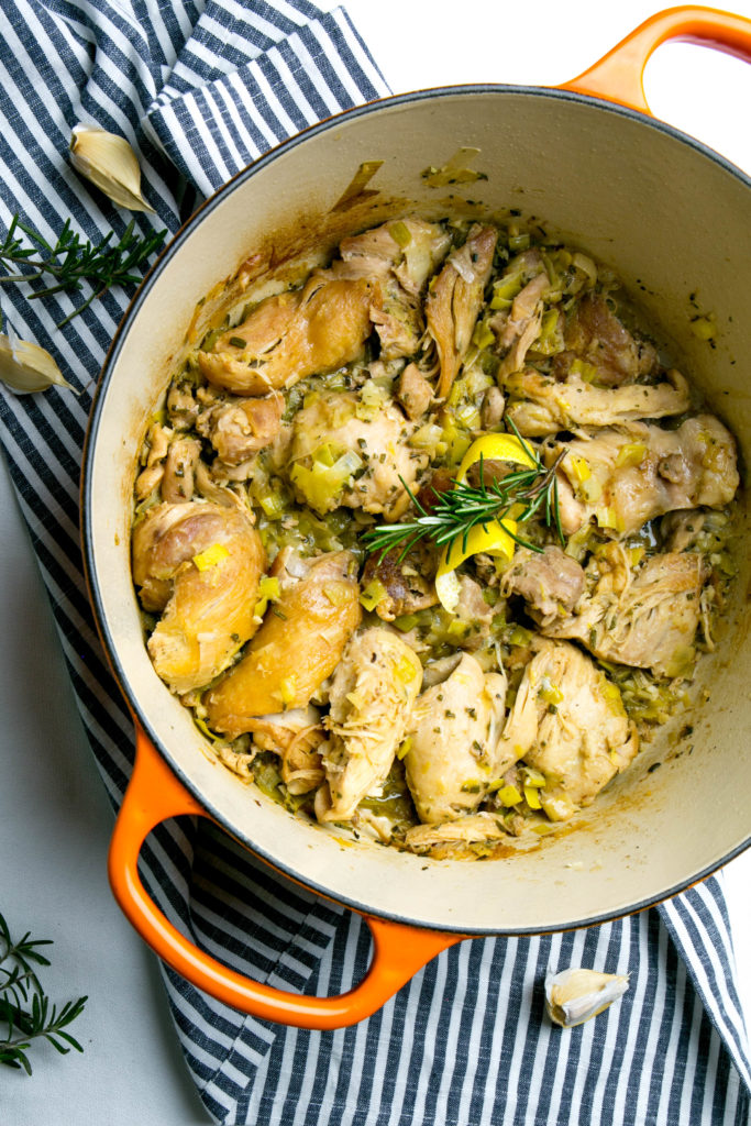 Chicken thighs in a dutch oven with rosemary and lemon