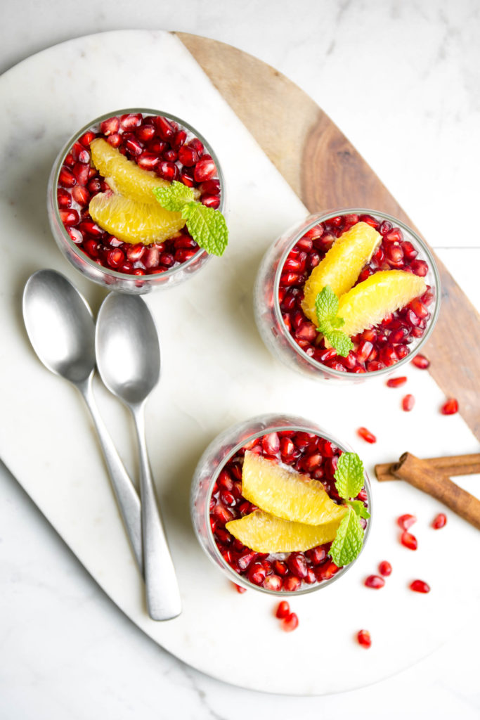 Three pomegranate and orange chia seed pudding with spoons