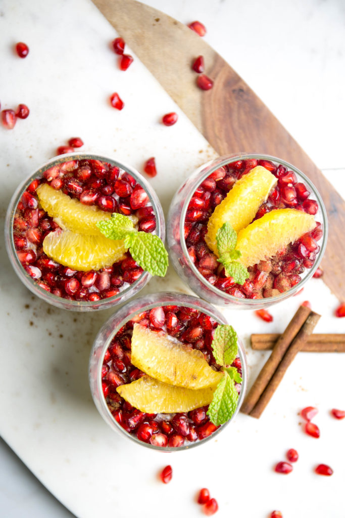 Three chia seed puddings with pomegranate seeds and oranges