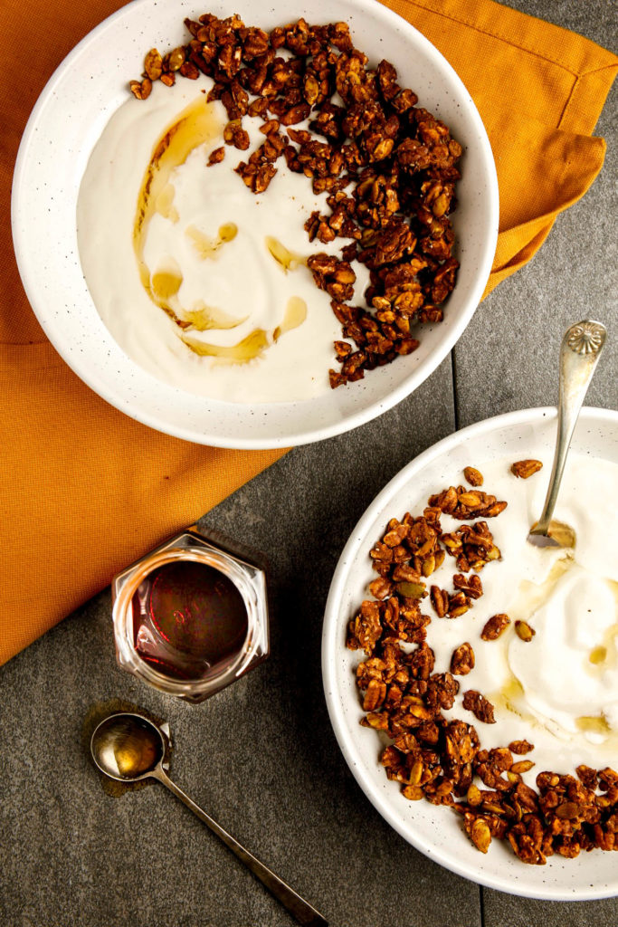 Pumpkin spice granola in a bowl of yogurt with maple syrup