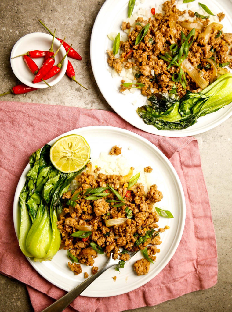 Two plates of Spicy Thai Basil Pork with bok choy, Thai chiles and lime