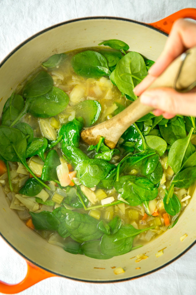 Large steaming soup pot of soup with spinach 