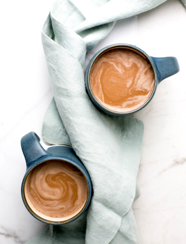 Two mugs of hot chocolate with a blue linen