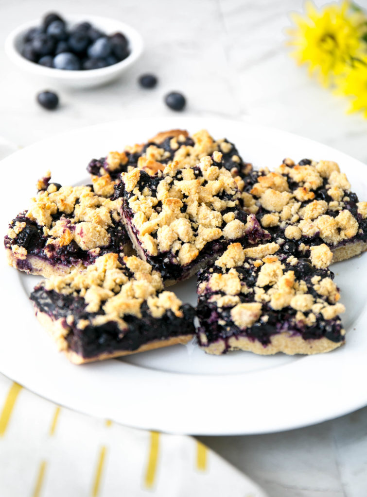 crumble bars on a plate with flowers and fresh blueberries