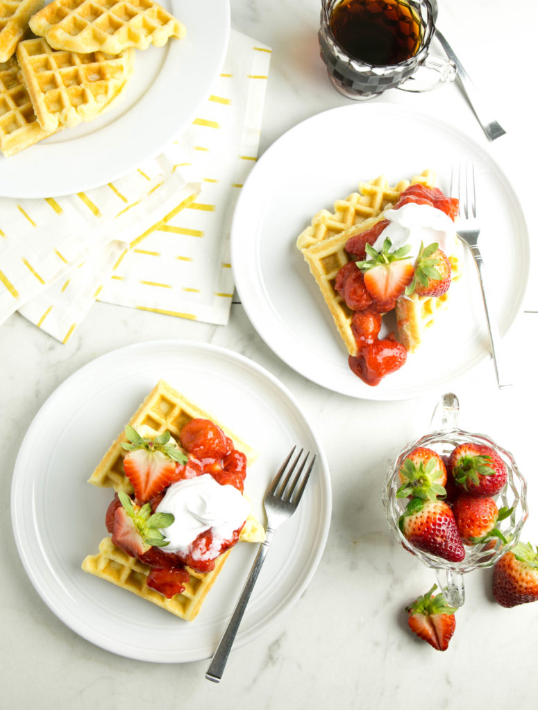 Two plates of waffles with strawberries