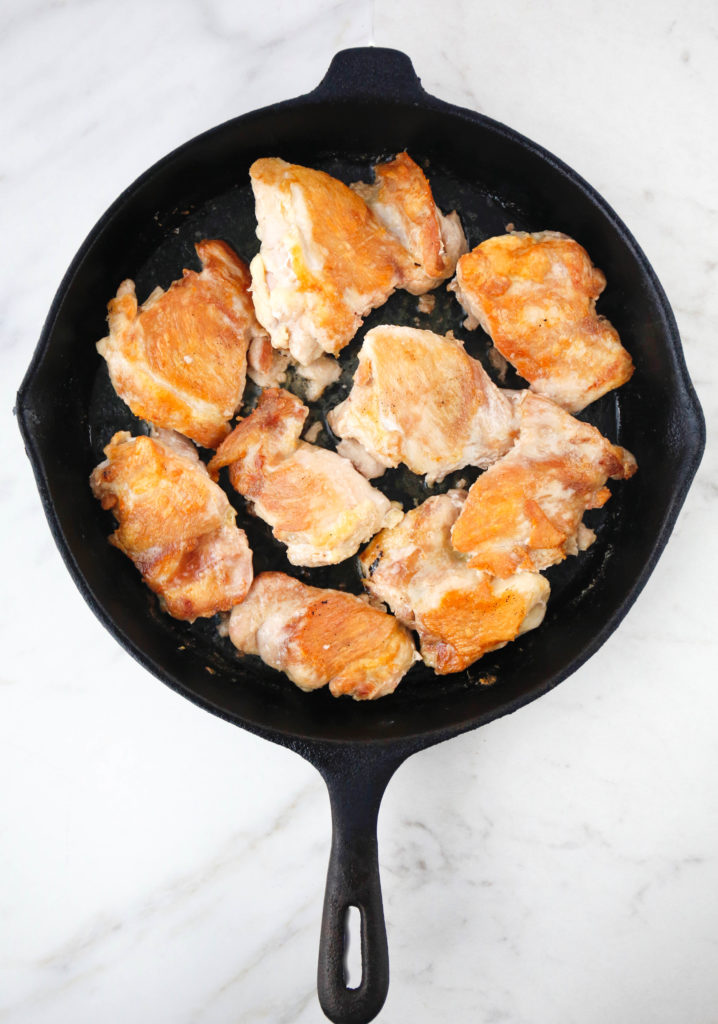 Browned chicken thighs in a cast iron skillet