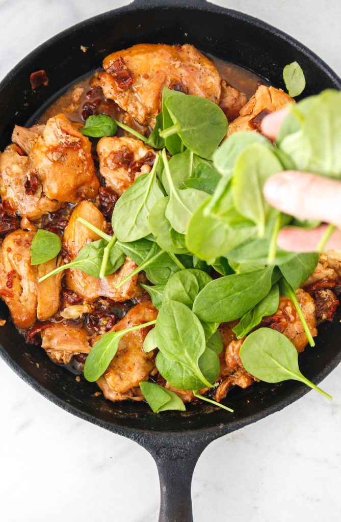 chicken thighs in a cast iron skillet with spinach