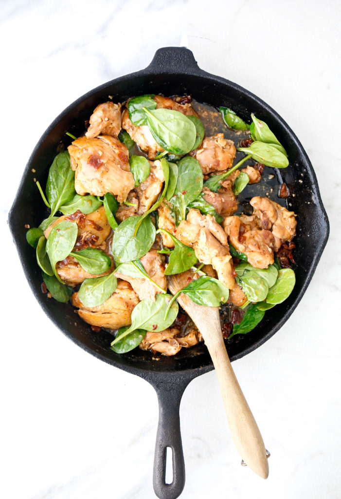 sun-dried tomato and spinach chicken thighs in a cast iron skillet