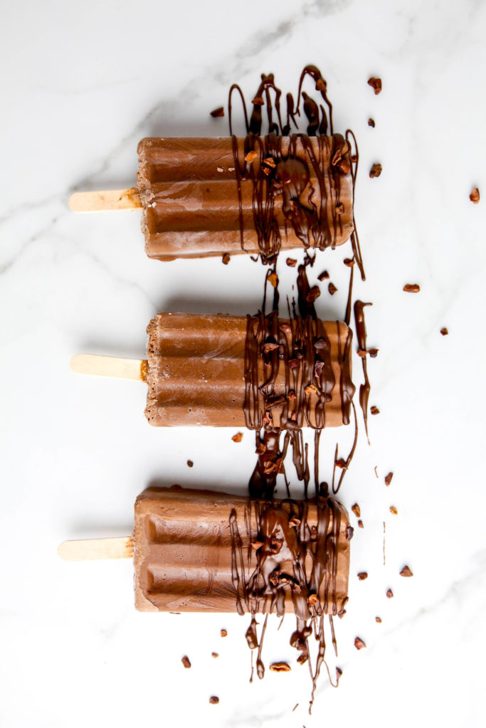 Three fudgesicles drizzled with chocolate and cacao nibs