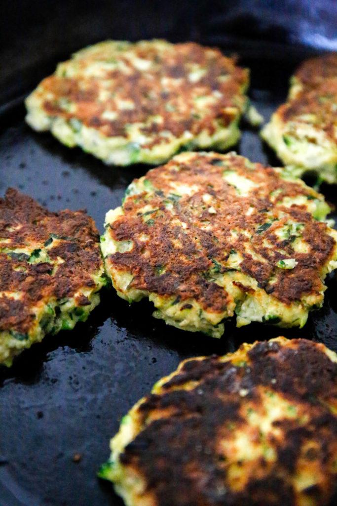 zucchini fritters cooking in a pan