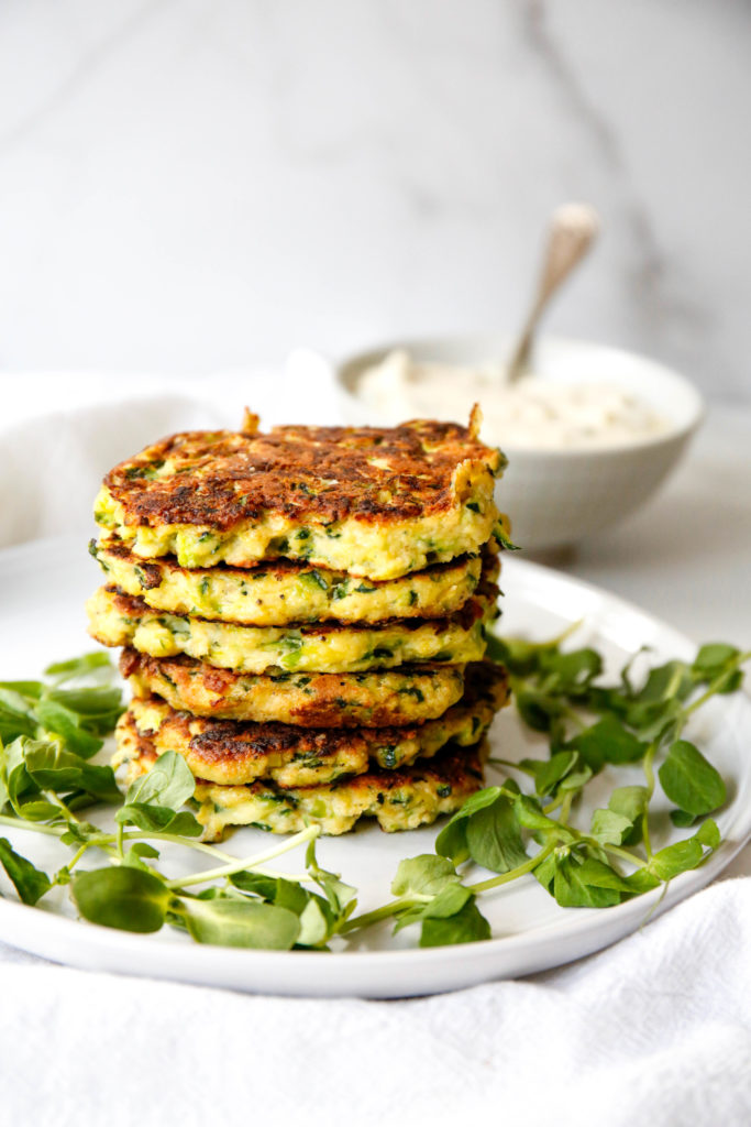 six zucchini fritters stacked on top of one another