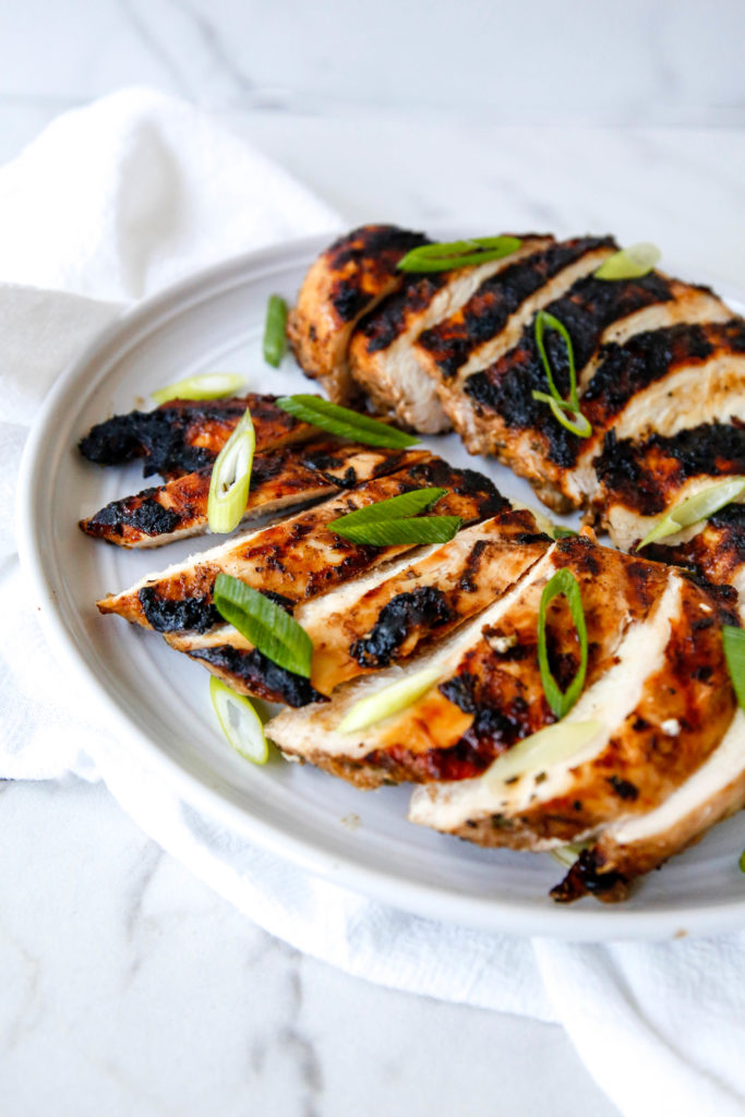 the best grilled chicken sliced on a plate with scallions