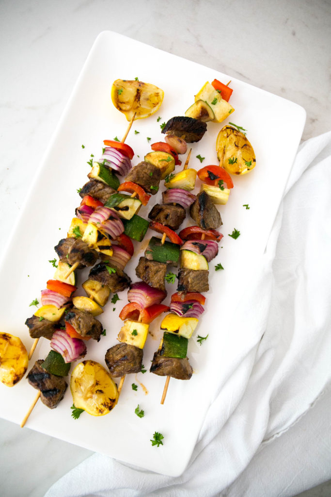 beef skewers on a white rectangle plate