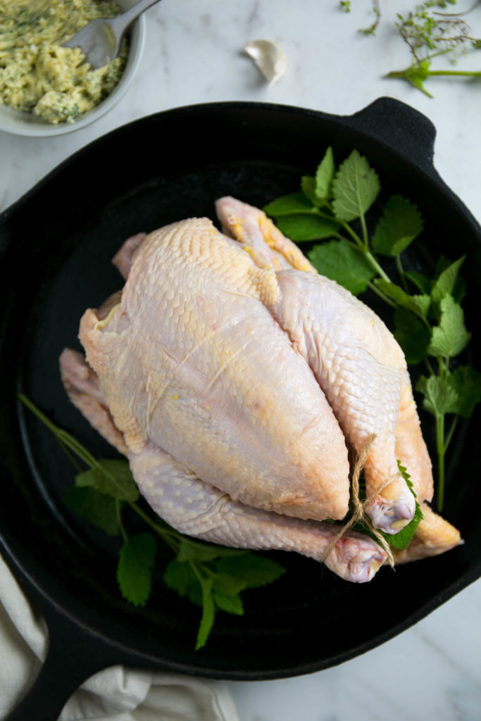 an uncooked chicken on a cast iron skillet
