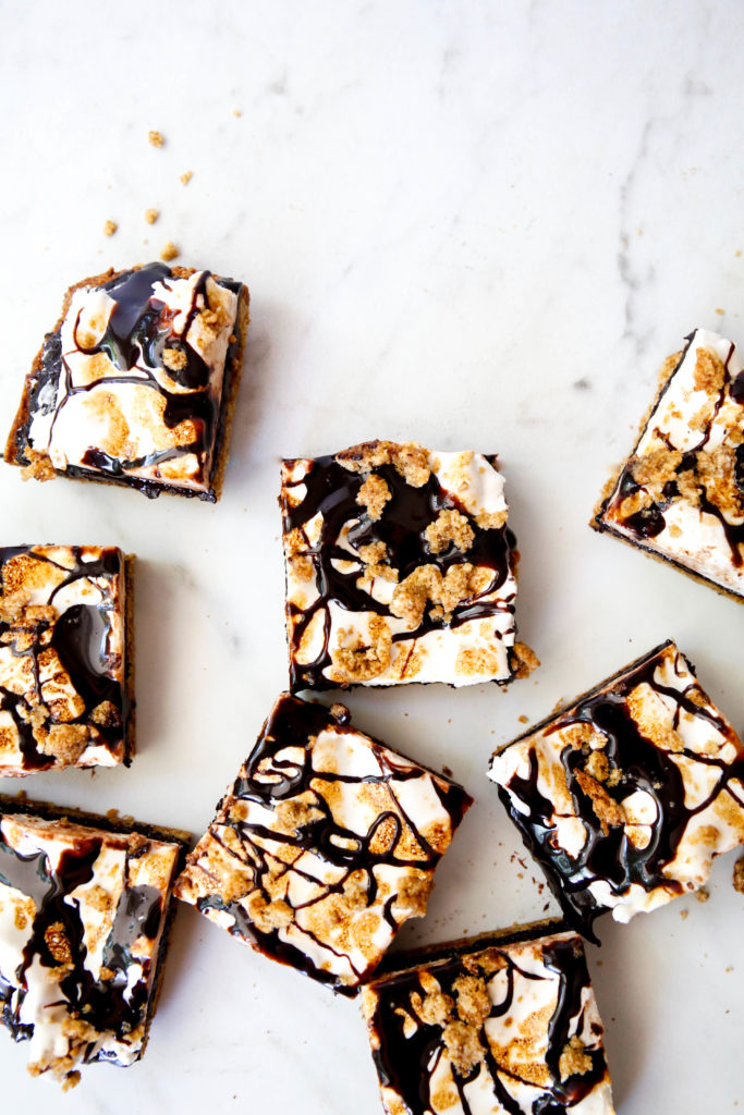 s'more bar squares with chocolate topping, crumbled graham crackers and marshmallow