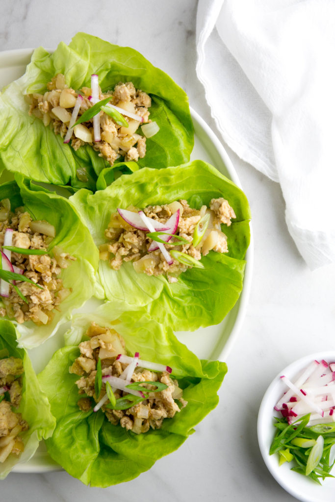 Aerial view of chicken lettuce wraps with radishes and scallions