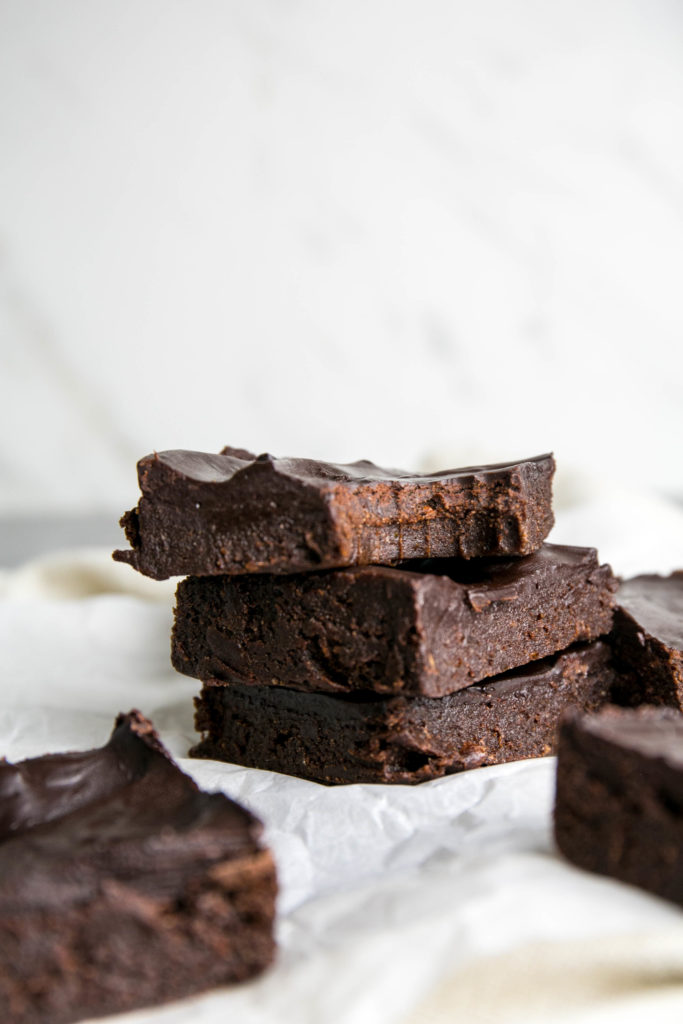 three raw chocolate brownies stacked on top of each other with a bite out