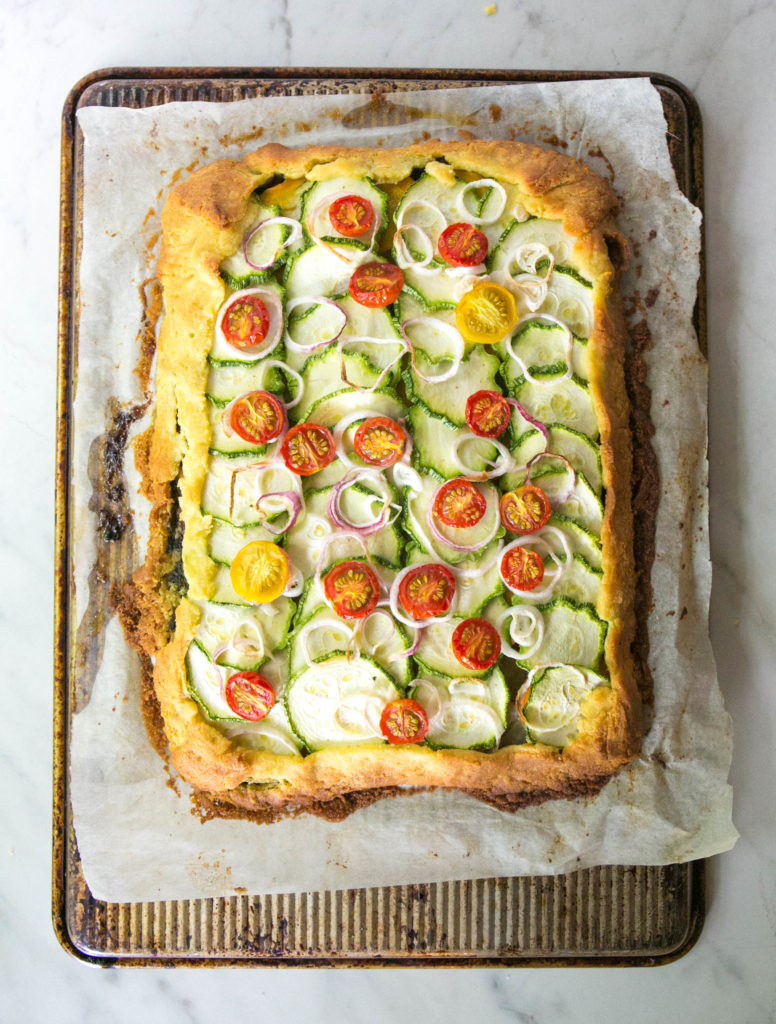 zucchini flatbread on the back of a baking sheet with vegetables