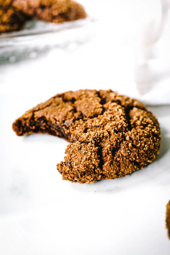 Up close picture of a molasses cookie with a bite taken from it