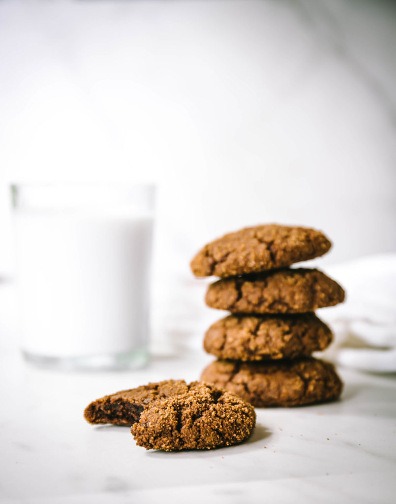 Four stacked molasses cookies with one that has a bite taken out of it