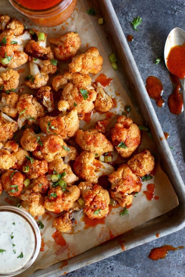 Cauliflower Buffalo Bites from The Real Food RD's on a sheet tray with buffalo sauce and ranch