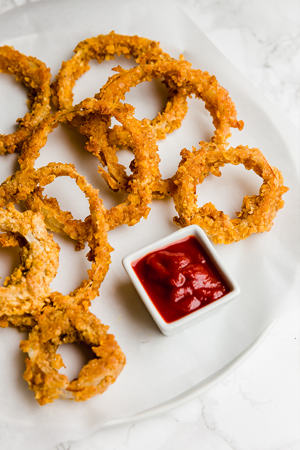 Baked Onion Rings from Unbound Wellness on a plate with ketchup on the side