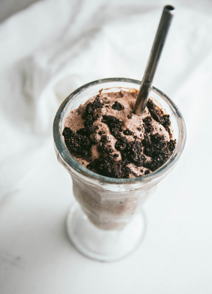 Cookies and cream milkshake with a straw and crumbled cookies on top