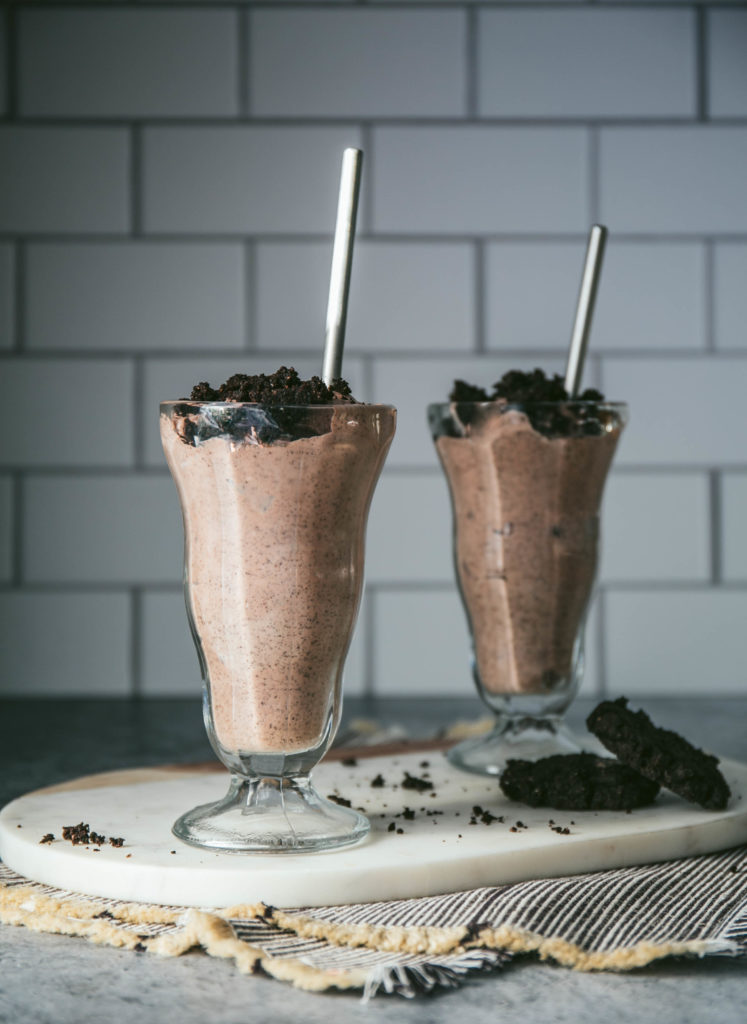 Two cookies and cream milkshakes in glasses with straws