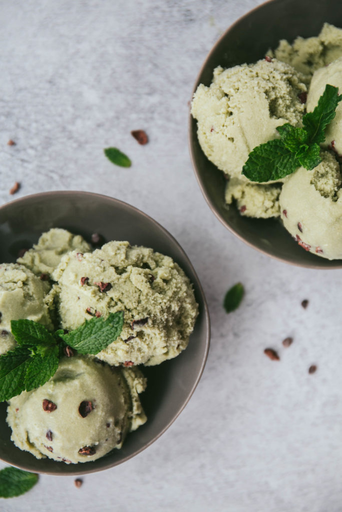 Two bowls of ice cream with cacao nibs and fresh mint