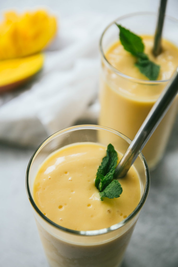 Two mango lassi smoothies with mint and straws