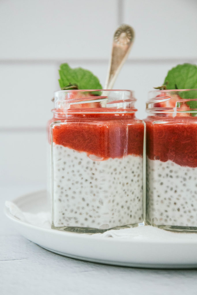 Strawberry rhubarb chia seed pudding in two glass jars with spoon