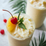 Two virgin pina coladas with pineapple and cherry garnishes