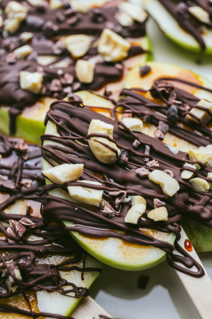 Chocolate covered caramel slices with chopped cashews and cacao nibs