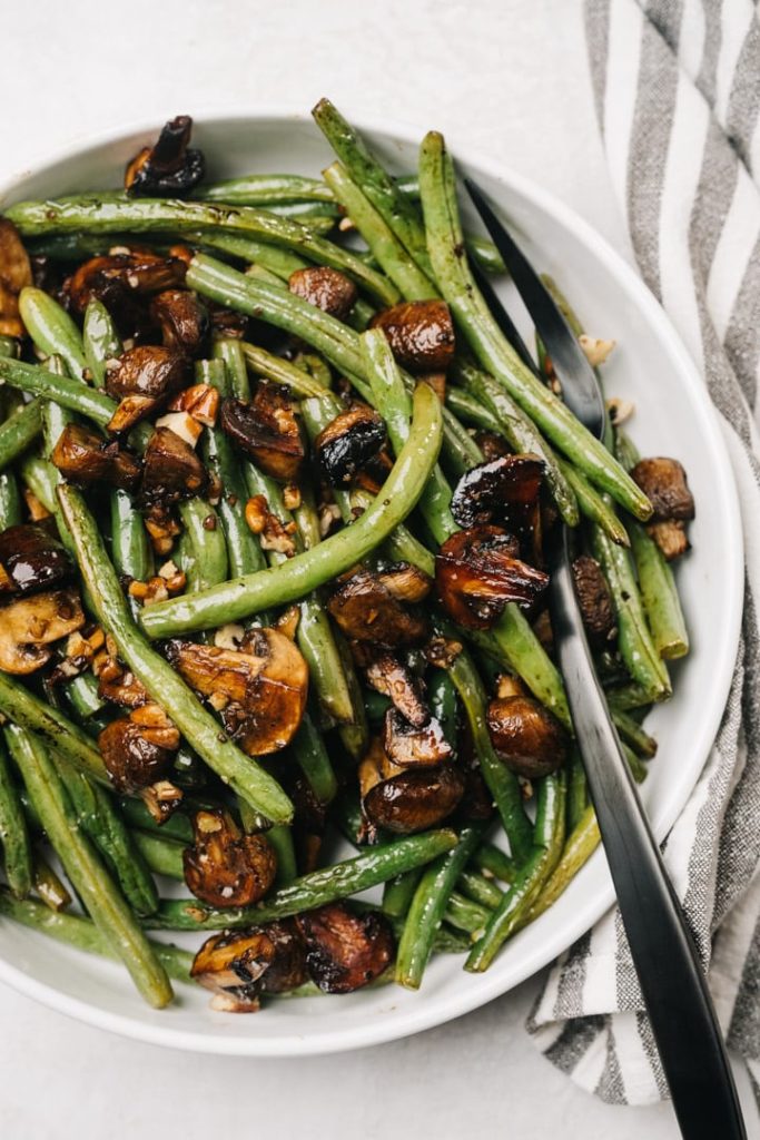 Green beans and mushrooms with a serving spoon and napkin