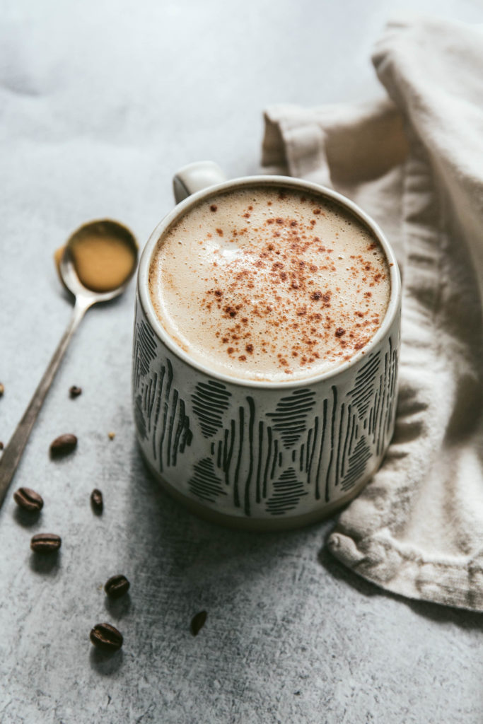 Maple tahini latte with coffee beans and a napkin