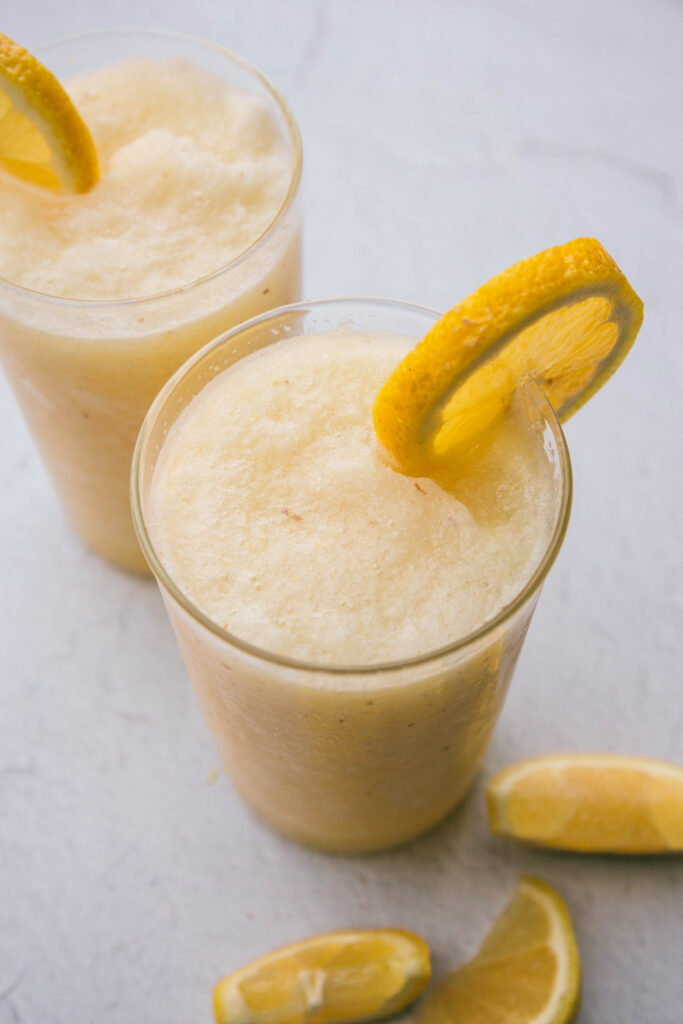Frozen lemonade in two glasses with fresh lemon slices on the rim
