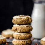 Pumpkin cookies stacked on top of each other with milk